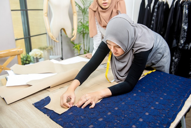 Foto stilista musulmano della donna che appunta il modello di carta su tessuto