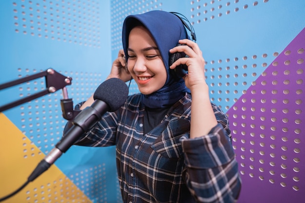 Muslim woman girl is recording a podcast in her studio