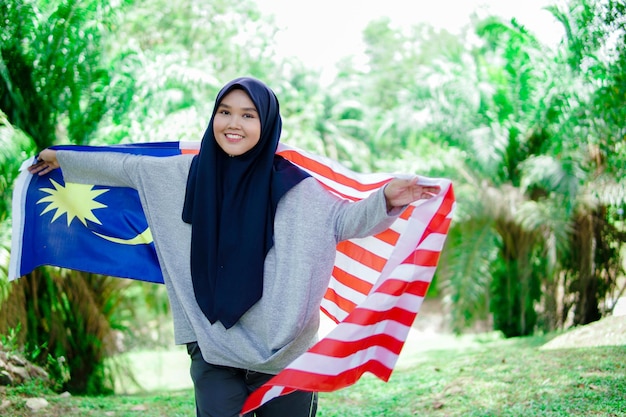 Muslim woman happy holding a malaysian flag malaysia independence day