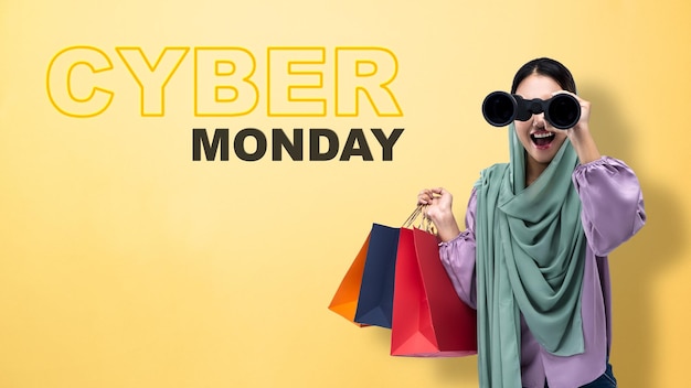 Photo muslim woman in a headscarf holding a binocular and shopping bags cyber monday concept
