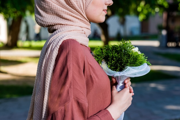 花を保持しているヒジャーブのイスラム教徒の女性