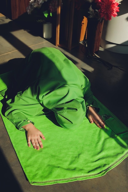 Muslim woman in hijab praying on mat indoors