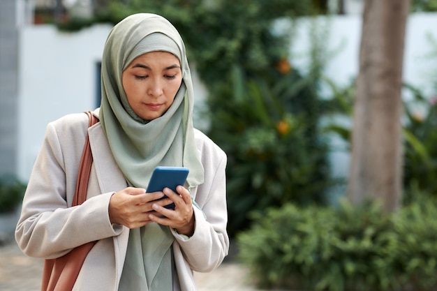 Photo muslim woman in hijab reading text messages on smartphone