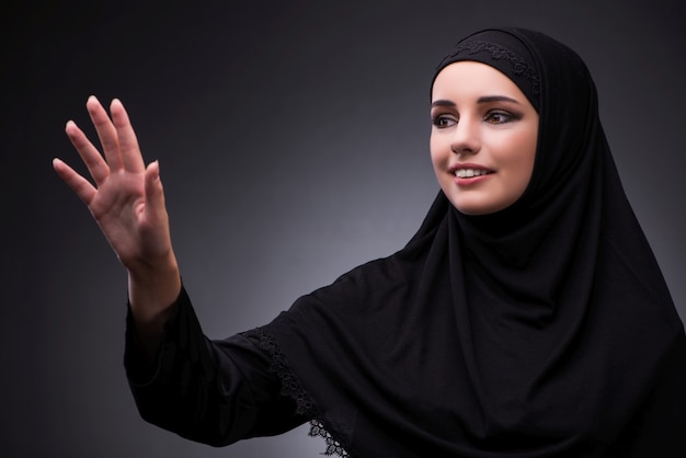 暗い背景に対して黒のドレスでイスラム教徒の女性
