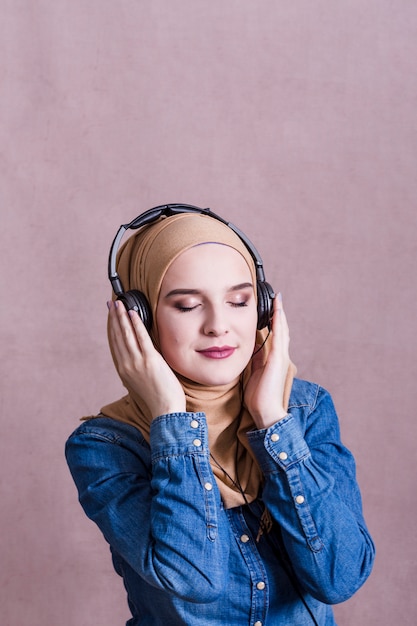 Photo muslim woman listening to music on headphones