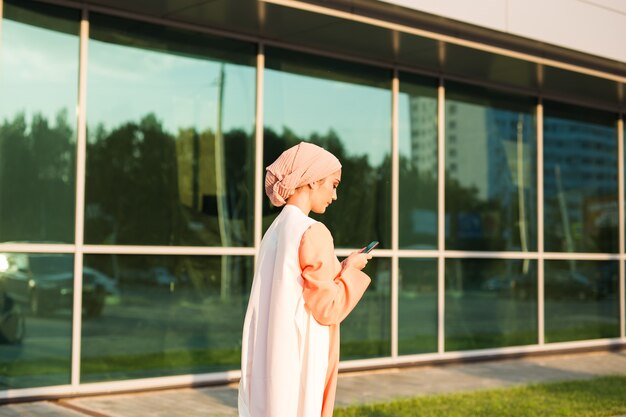 Muslim woman messaging on a mobile phone in the city.