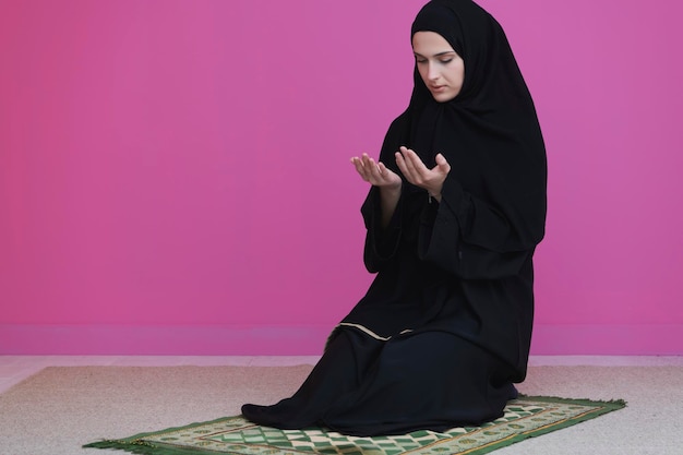 Muslim woman in namaz praying to allah, god. muslim woman on\
the carpet praying in traditional middle eastern clothes, woman in\
hijab