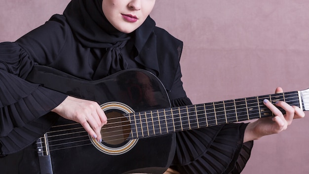 Muslim woman playing on the guitar