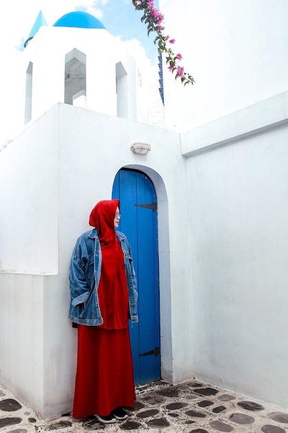 Muslim woman posing on Santorini traditional blue wooden door and blue domes