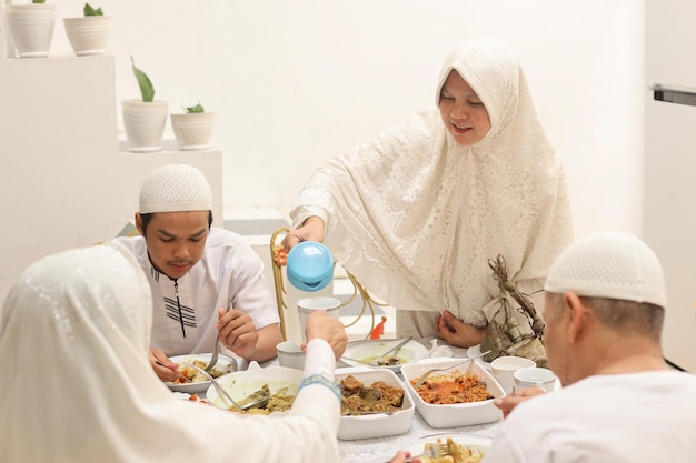 Muslim woman pouring water to her mother glass at the dining room during the Eid Mubarak