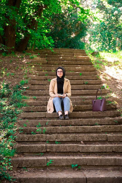 Muslim woman reading a book in the park during hers free time.