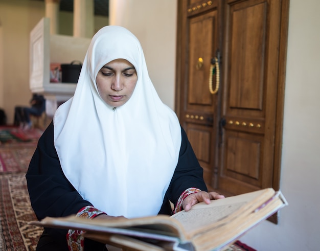 Foto donna musulmana leggendo il corano e pregando nella moschea