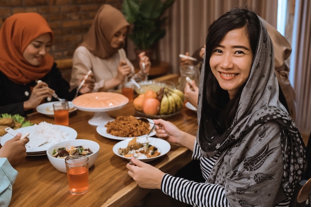 夕食しながら笑顔のイスラム教徒の女性