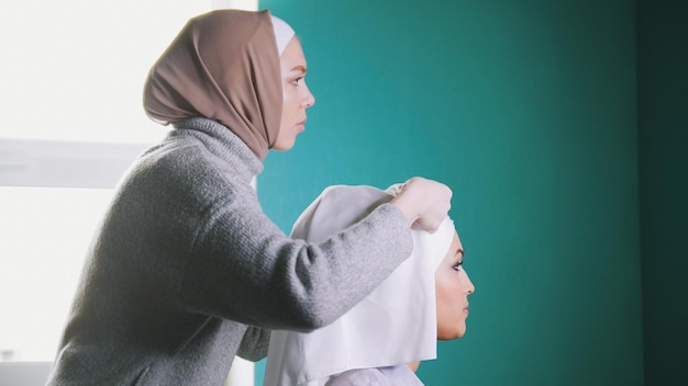 매력적인 신부를 위해 이슬람 터번을 묶는 이슬람 여성
