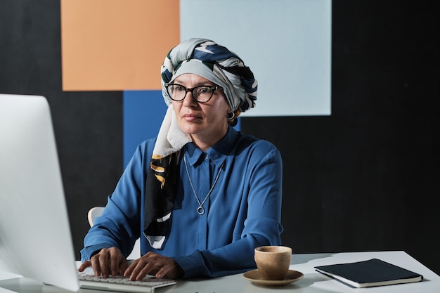 Muslim woman typing on computer at office