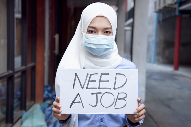 Donna musulmana che indossa una maschera per il viso senza soldi a causa dell'interruzione del lavoro tagliato dopo che la pandemia di covid19 ha portato la recessione economica