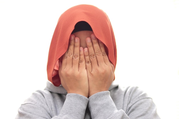 Muslim woman wearing hijab covering hiding face with her hands shy afraid worried guilty gesture