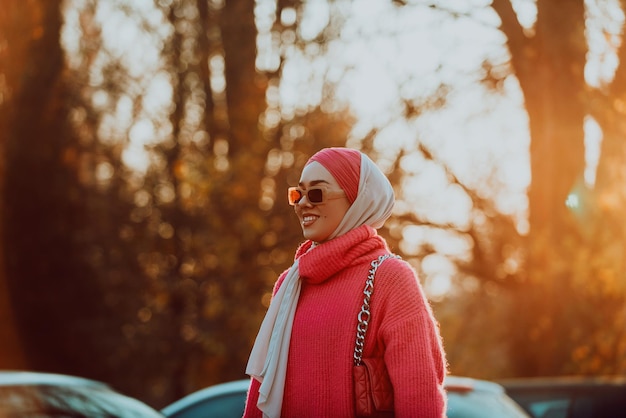 A Muslim woman wearing a hijab walks the streets of the city in a modern outfit combined with sunglasses Selective focus