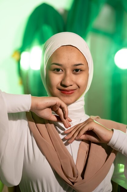 白いスカーフと白い服を着たイスラム教徒の女性が両手でポーズをとる