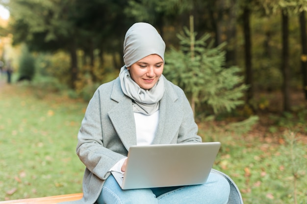 Muslim woman with her laptop in the park.