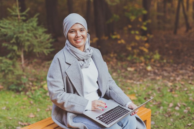 Muslim woman with her laptop in the park.