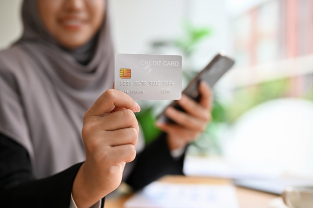 Muslim woman with hijab holding a smartphone and credit card Online payment internet banking