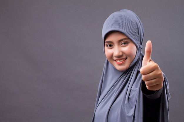 Muslim woman with hijab pointing thumb up