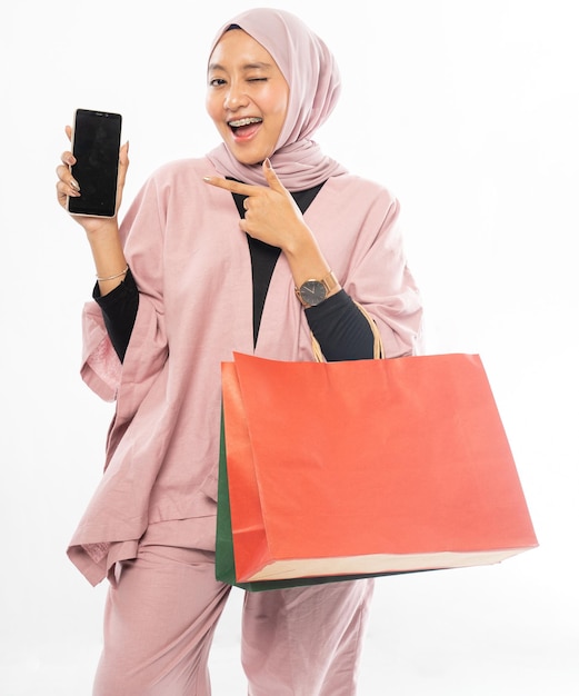 Muslim woman with hijab shopping while showing her mobile phone