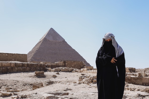砂漠でサラートを祈るローブの服を着たイスラム教徒の女性