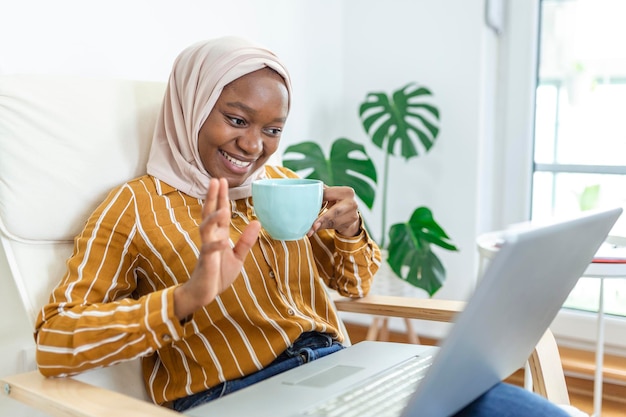 Muslim woman working with computer Arab Young business woman sitting at her desk at home working on a laptop computer and drinking coffee or tea Muslim woman working at a home and using computer