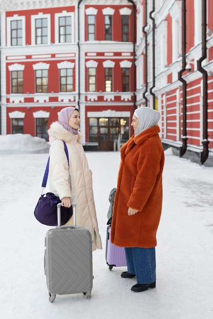 Photo muslim women walking with their luggage to the hotel while being on vacation