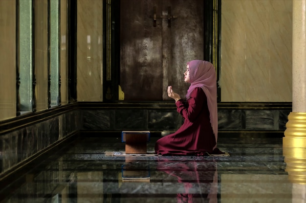 Muslim women wearing red shirts Doing prayer According to the principles of Islam.
