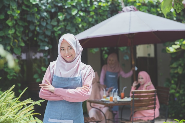 Muslim young business owner standing in front of her cafe