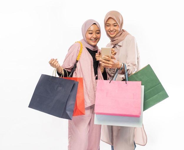 Photo muslim young friend using smart phone and holding shopping bag