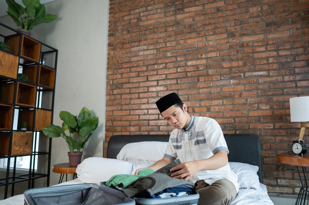 Muslim young man preparing and packing clothes