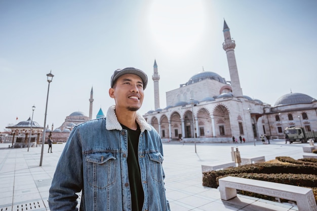 Muslim young man standing in front of the mosque and mevlana museum in konya turkey