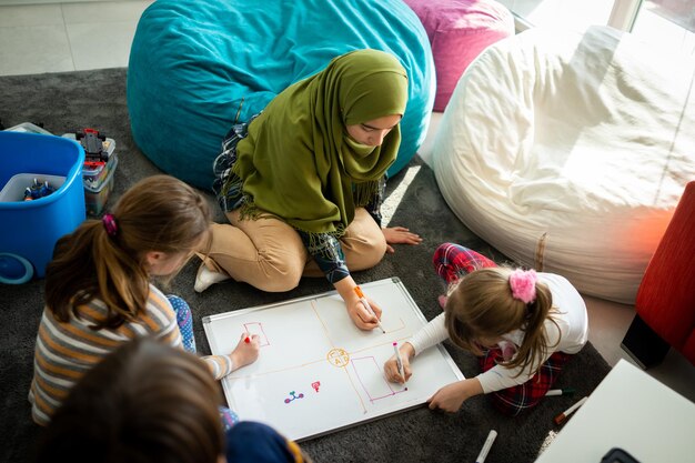 Фото Молодая мусульманская учительница с небольшой группой детей, обучающихся в школе