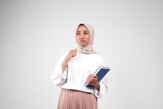 Foto collegio muslimah portando libro e penna per lo studio di sfondo bianco isolato