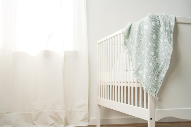 Muslin baby blanket hanging on childs bed in nursing room