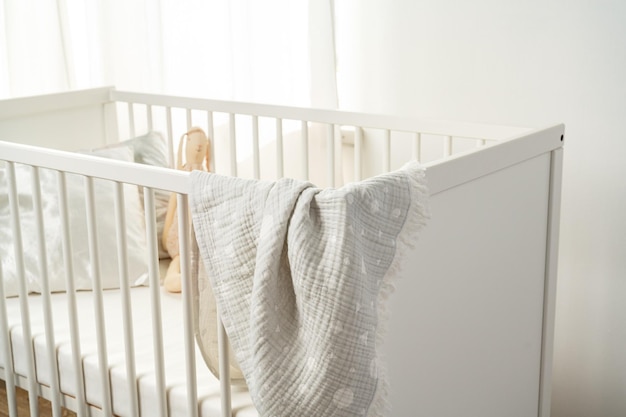 Муслинное детское одеяло висит на детской кровати в детской комнате