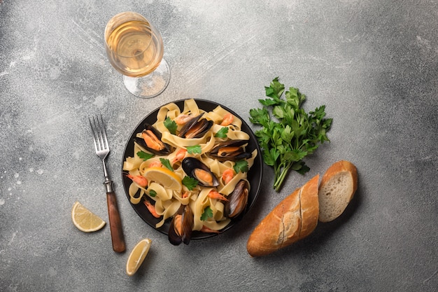 Mussels, bread toasts and white wine on stone table. Top view with copy space.