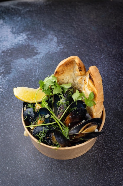 Mussels in a cardboard disposable plate with lemon and\
parsley