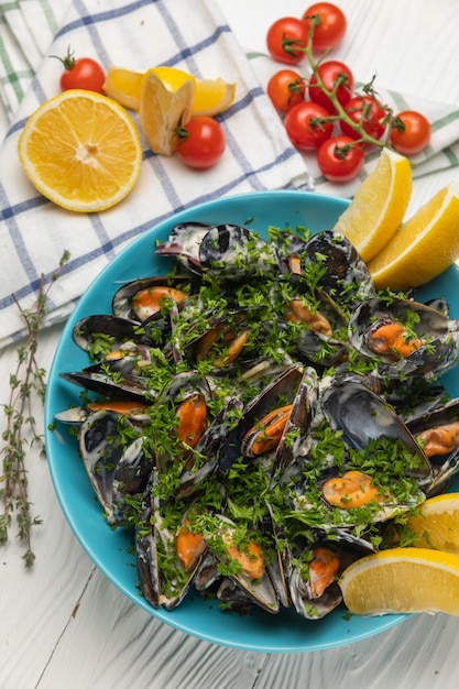 Mussels in a plate with lemon on a white table