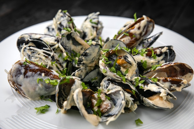 Mussels in sauce on a dark table