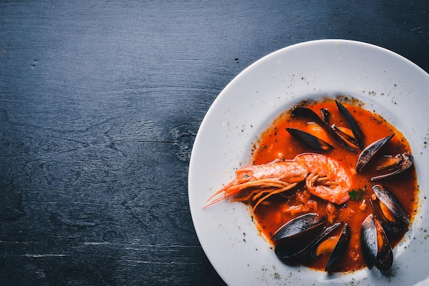 Cozze e gamberi tigre in salsa di pomodoro cibo tradizionale italiano su uno sfondo di legno vista dall'alto spazio libero per il testo