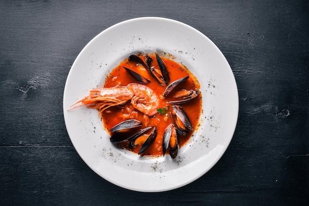 Mussels and tiger prawns in tomato sauce Italian traditional food On a wooden background Top view Free space for your text