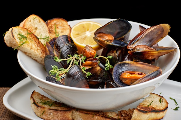 Mussels on a white plate on a wooden board