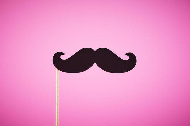 Mustache on a stick isolated on pink background ai generative