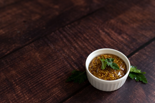 Mustard in the assortment: Dijon mustard , burning Russian mustard and dry grains in bowls on wooden background