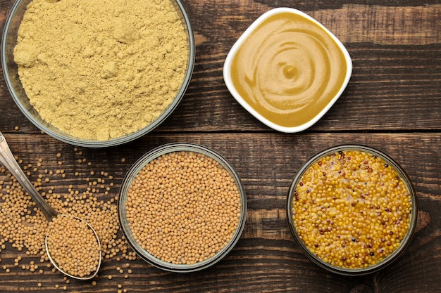 Mustard. Different types of mustard, dry mustard grains sauce and mustard powder in a bowl on a brown wooden table. close-up. view from above